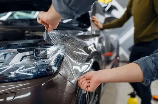 Tehnician aplicand folie PPF pe bara fata a unei masini